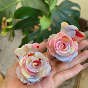 Detailed view of rose flower hair claws with colorful marble texture held in hand