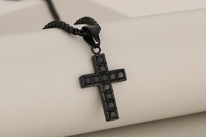 Macro shot of black stainless steel cross pendant with inlaid black square gemstone