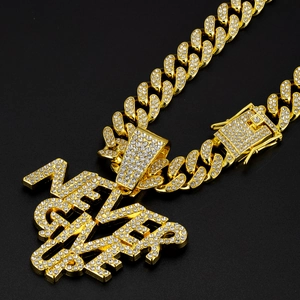 Close-up of golden iced-out EVER pendant with sparkling rhinestones on Cuban link chain