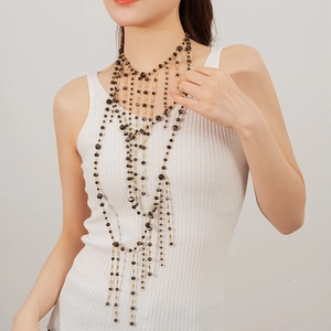 Close-up of multilayered black beaded waterfall necklace with golden tassel details