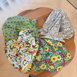 Flat lay of four floral cotton tote bags in diverse patterns on a wooden table