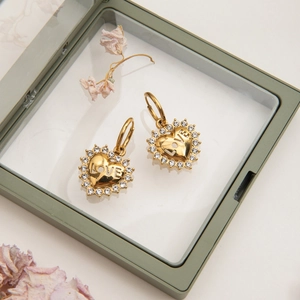 Close-up of golden heart earrings with crystals and LOVE engraving in a jewelry box