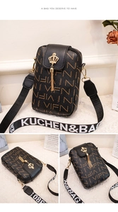 Detail of black monogram crossbody bag with golden crown clasp and fringed tassel