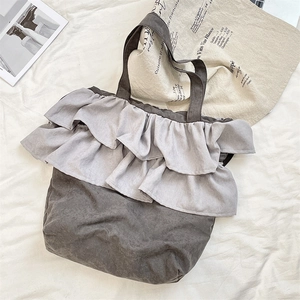 Close-up of gray cotton linen tote bag with tiered ruffle design and neutral tones