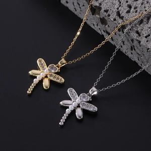 Macro detail of dragonfly pendants with pavé wings, heart stones, and pearl bodies