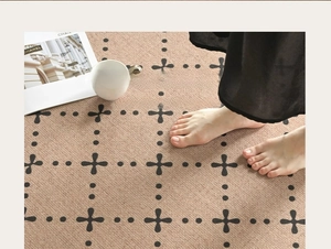Detail of light beige woven rug with black polka dots and cross-line grid pattern