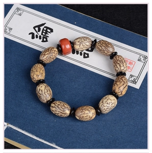 Detail eines Bodhi-Samen-Armbands mit roter Perle auf einem blauen Vintage-Buch