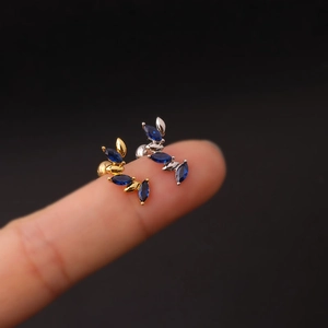 Detailed view of 16G stainless steel leaf studs with blue zircon in gold and silver
