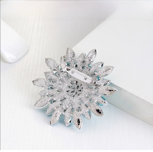 Macro detail of silver flower brooch back showing safety pin clasp and blue crystals