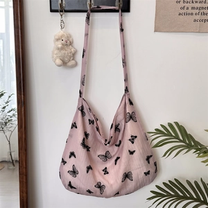 Close-up of pink lace shoulder bag featuring black butterfly prints and a soft plush pendant