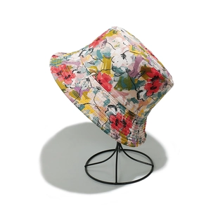 Close-up of vibrant floral print bucket hat displayed on a black metal mesh stand