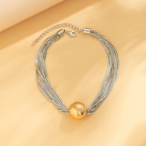 Close-up of silver multilayer chain necklace with a central gold bead and lobster clasp