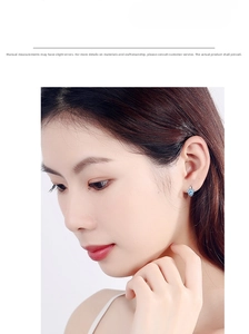 Close-up of paw print earring with blue zircon stone on model ear lobe