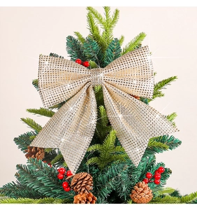 Close-up of sparkling champagne gold Christmas bow with sequins on a tree branch
