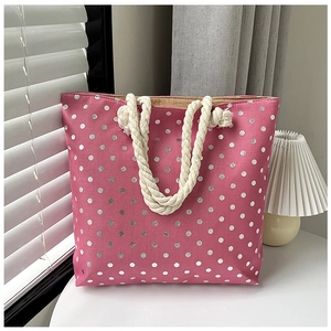 Detail view of pink canvas tote bag with silver polka dots and beige rope handles