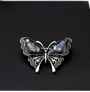 Detailed close-up of shell wings and hollow metal pattern on silver butterfly brooch