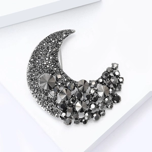Macro view of crescent moon brooch featuring dark grey rhinestones on a silver base