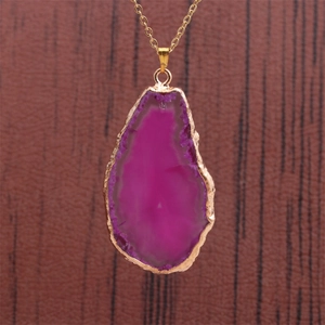 Détail macro du pendentif en tranche d'agate rose rouge avec bords dorés sur chaîne