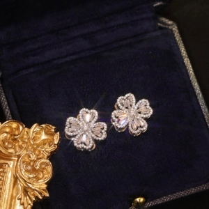 Macro shot of silver clover stud earrings with sparkling crystals on blue velvet