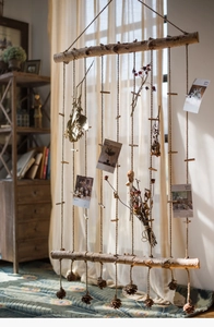 Detail of hanging wooden branch photo display with natural pine cones and hemp ropes