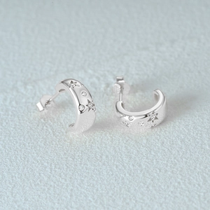 Detailed macro view of S925 sterling silver C-hoop earrings with star engraving and cubic zirconia