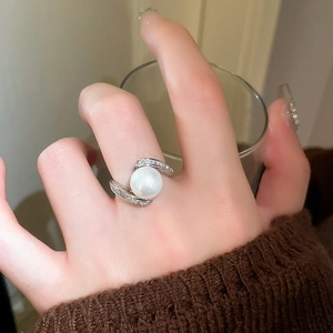 Détail macro de bague serpent argentée avec perle blanche et micro-pavage de zircons