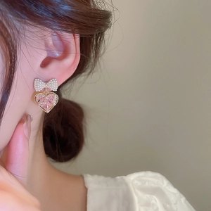Detail of bow and heart earrings featuring pink zircon and pearls on a model's ear