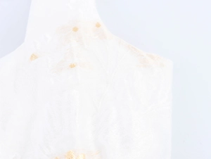 Dettaglio ravvicinato del tessuto bianco con elegante ricamo floreale dorato lucido