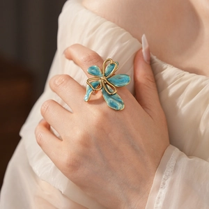 Detailed view of a vintage lake blue flower ring with gold trim worn on the finger
