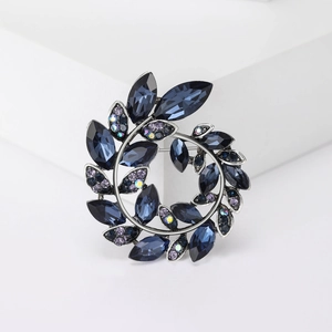 Elegant rhinestone olive branch wreath brooch with blue and purple crystals in metal finish