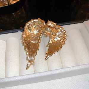 Detail of the golden angel wing brooch back with pin clasp and brushed metal finish