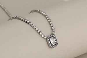 Detailed close-up of a silver tennis necklace with a radiant rectangular crystal pendant