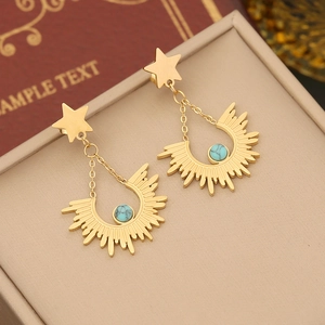 Gold celestial earrings with star and moon charms on elegant jewelry box display