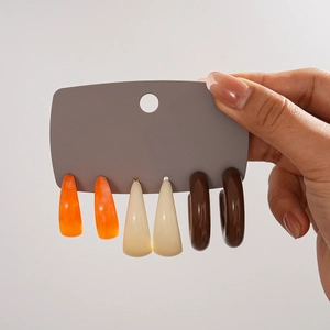 Drei Paar C-förmige Acryl-Ohrringe in den Farben Orange, Beige und Dunkelbraun