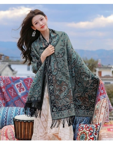 Close-up of thick teal paisley scarf with vintage floral patterns and black fringe tassels