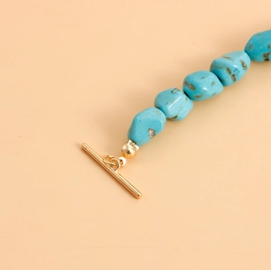 Macro detail of natural turquoise beads with a golden T-bar toggle clasp on a necklace