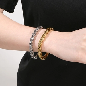 Close-up of gold and silver stainless steel linked chain bracelets on model's wrist