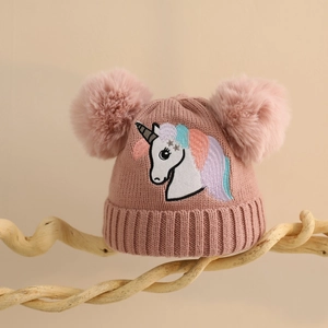 Detail der rosa Kinder-Strickmütze mit Regenbogen-Einhorn und flauschigen Kunstfell-Bommeln