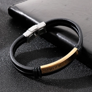 Detailed close-up of a double-layer black leather bracelet with a curved gold stainless steel plate