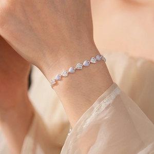 Close-up of lavender enamel and zircon heart-shaped bracelet on a woman's wrist