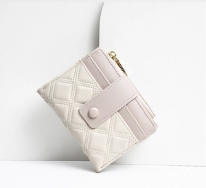Detail of cream and pink quilted PU leather wallet with snap closure and gold zipper