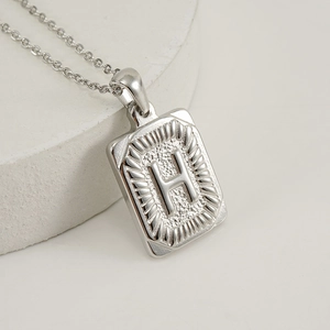 Polished silver stainless steel square pendant necklace featuring letter H design on white base