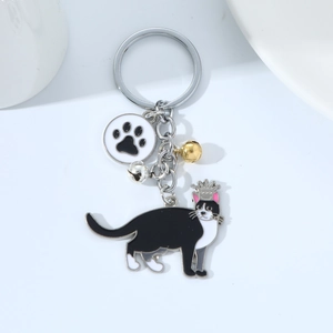 Detail of metal keychain featuring a black and white cat charm with cat paw and bells