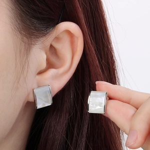 Close-up of minimalist square shell earrings with silver metal frame on model