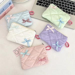 Close-up of quilted bow makeup bags in macaron colors with zipper and side handle