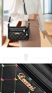 Detail of black pebbled leather bag with colorful diamond stitching and gold metal hardware