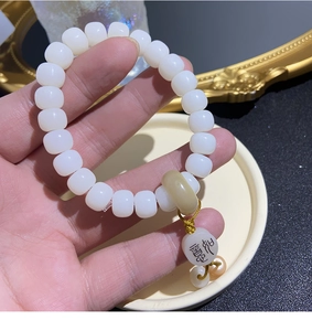 Macro detail of natural bodhi seed bracelet with yellow chalice pendant and peace charm