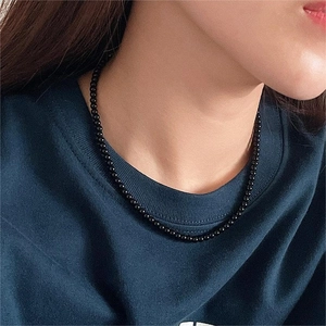 Minimalist 925 sterling silver black onyx beaded necklace shown on a model with blue hoodie