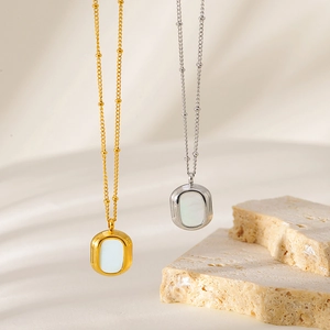 Detailed view of dual-color necklaces with white shell pendants on beaded chain links