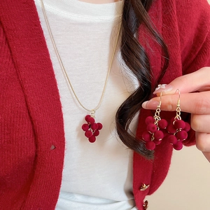 Detail of red flocked grape tassel necklace and earrings set worn by a model